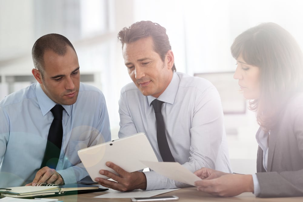 Business people meeting around desk with tablet