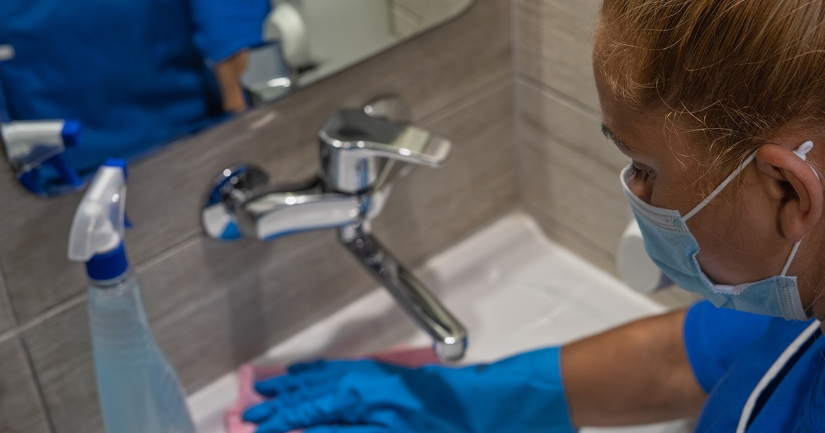 Hospital Housekeeper cleaning a sink in the bathroom