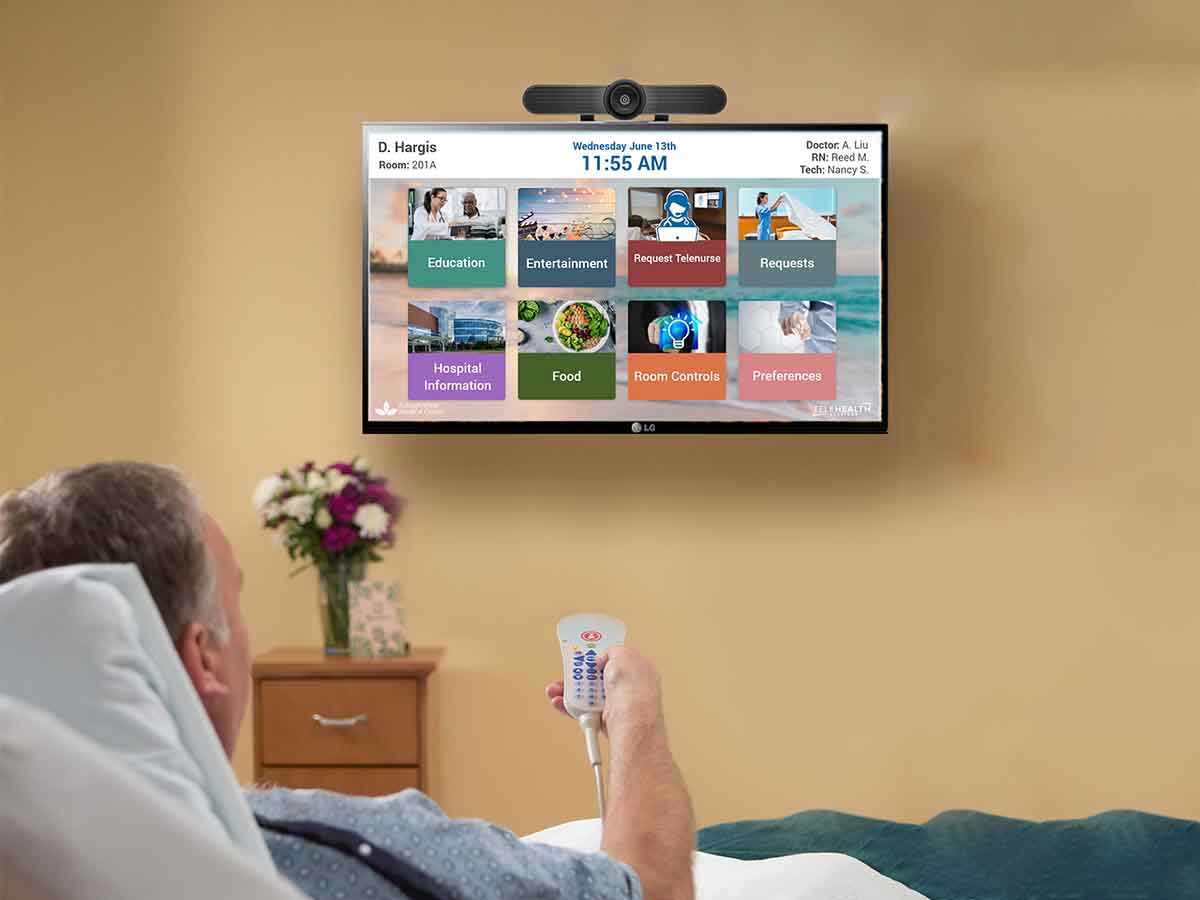 Patient in bed holding a remote watching television