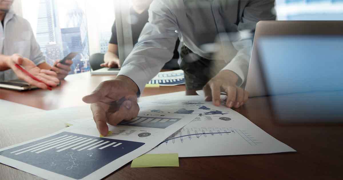 Double Exposure of hands pointing at a chart and computer scree