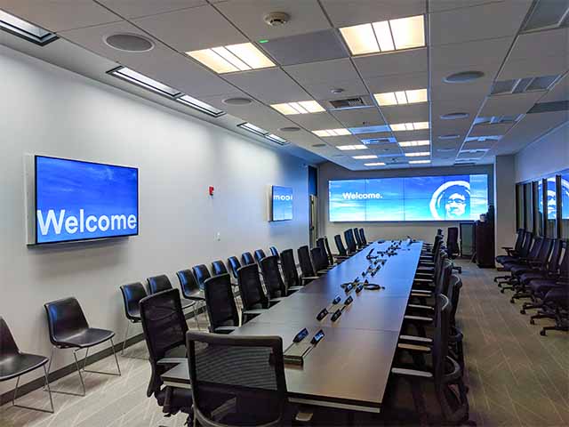 A board room with several displays and a video wall with a welcome message