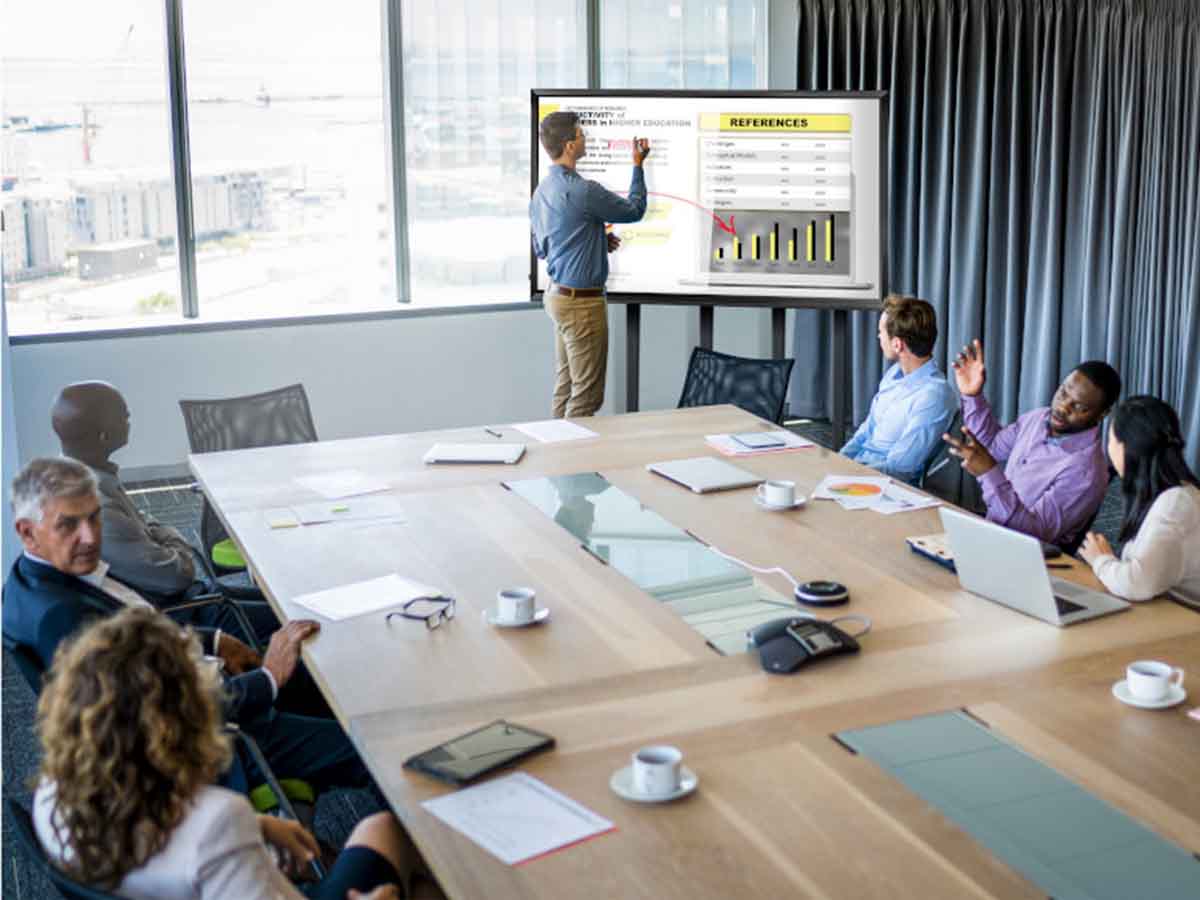 Several people in a meeting viewing a television with a presentation displayed