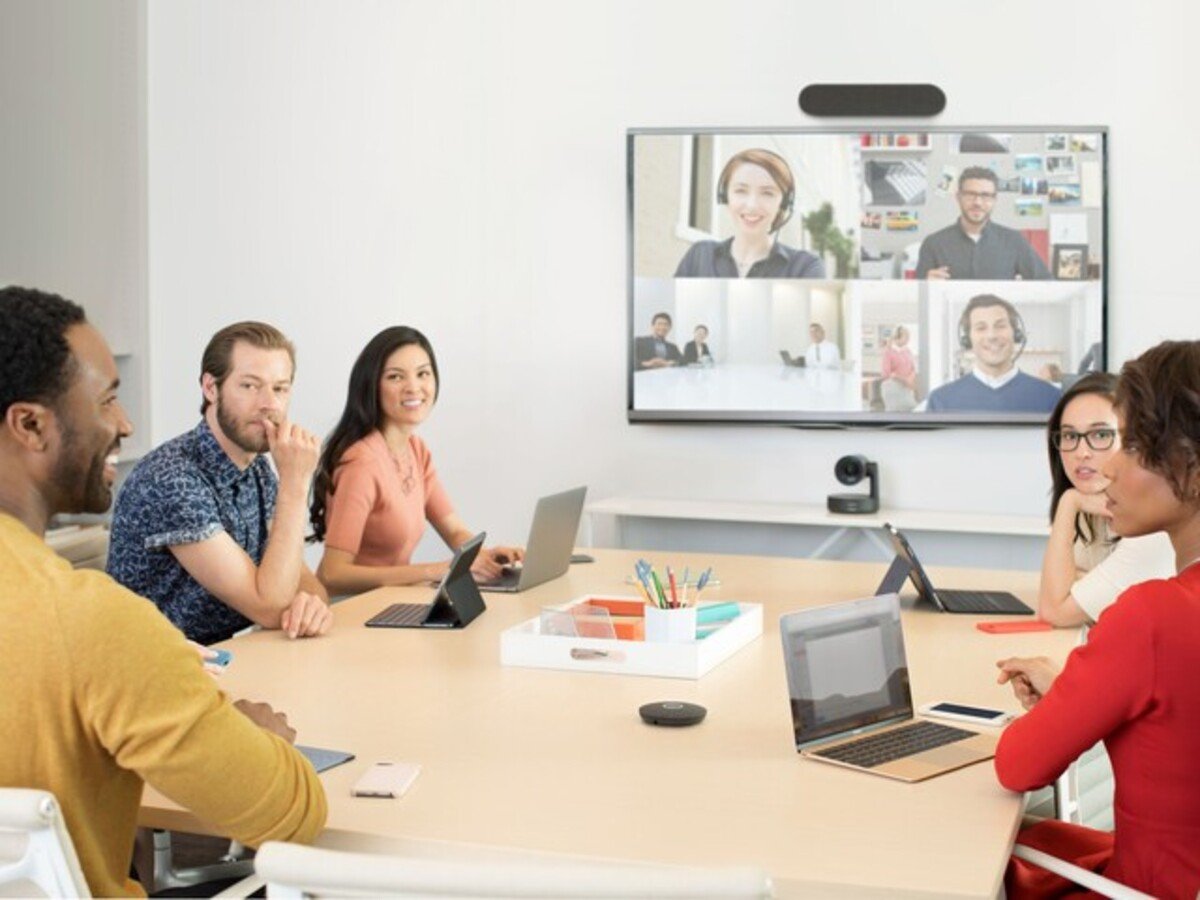 Virtual Meeting in a Conference Room with laptops and virtual participants on the screen