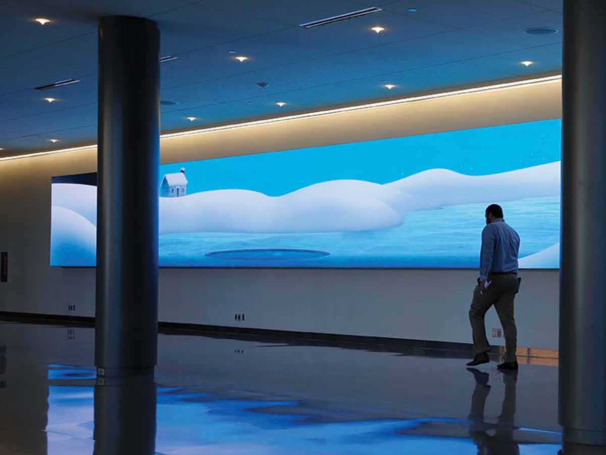 Man walking in front of a Dvled video wall