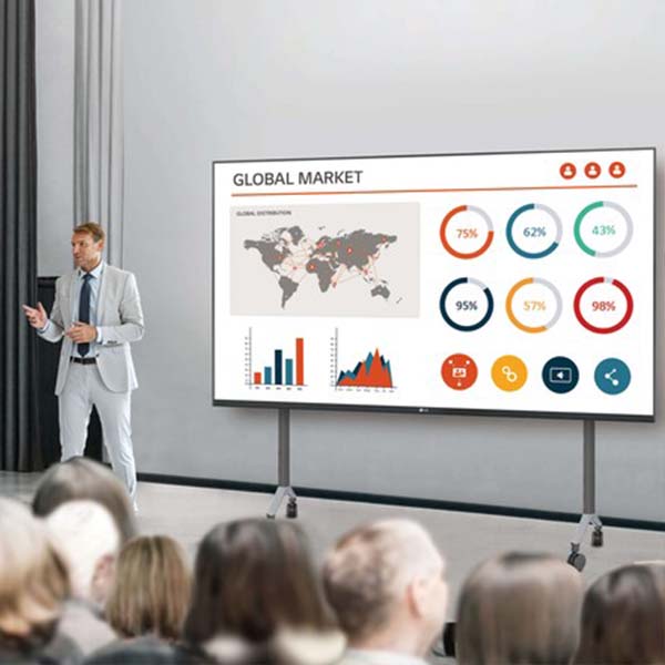 Man in a business suit give a presentation assisted by a digital display on a cart