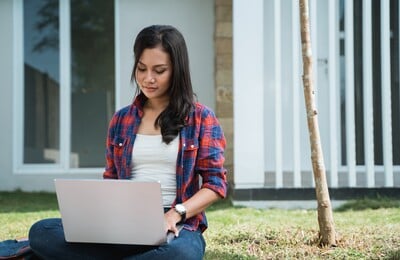Woman on a laptop sitting on the grass