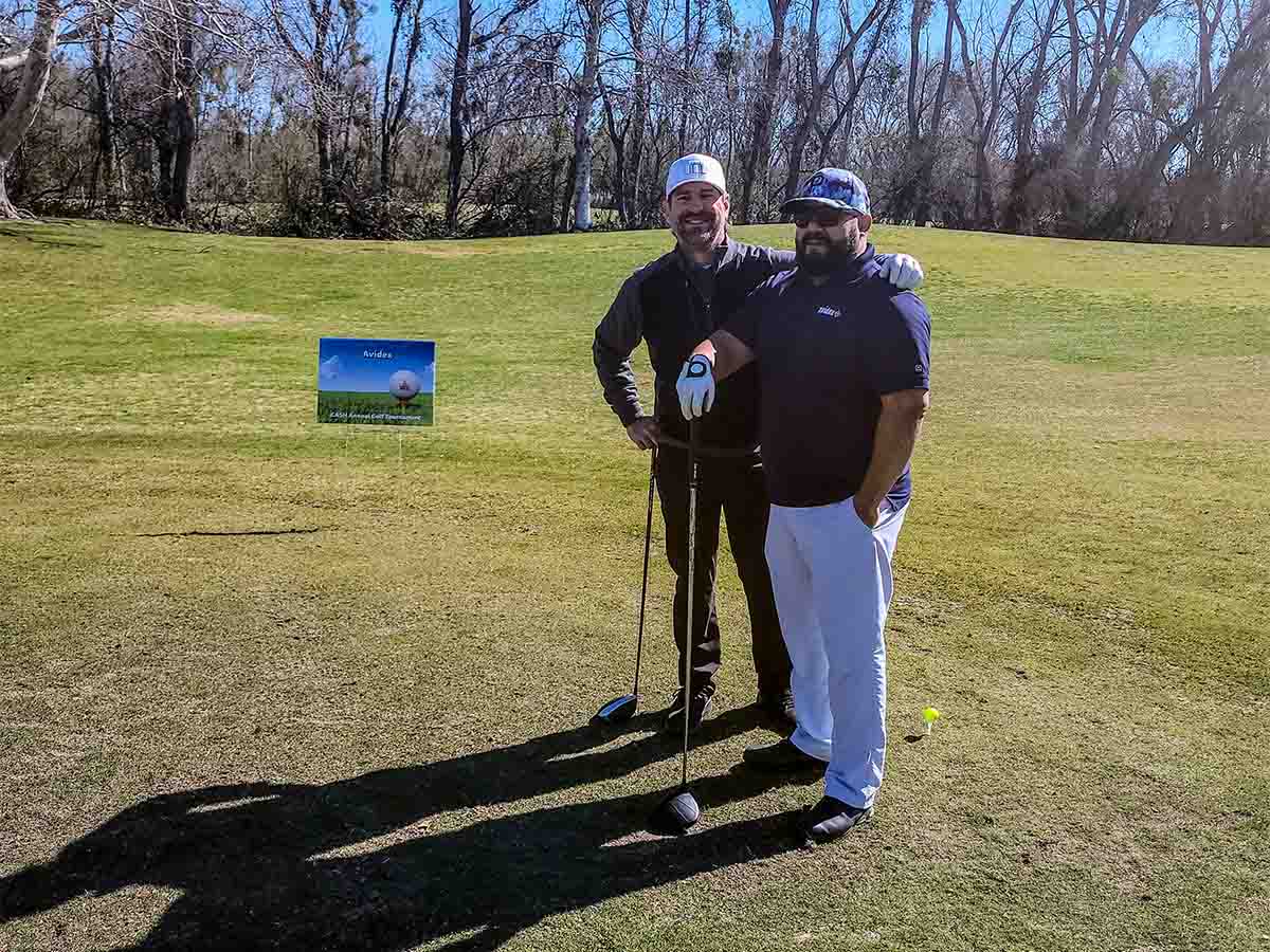 Two Avidex team members standing on a golf course holding drivers