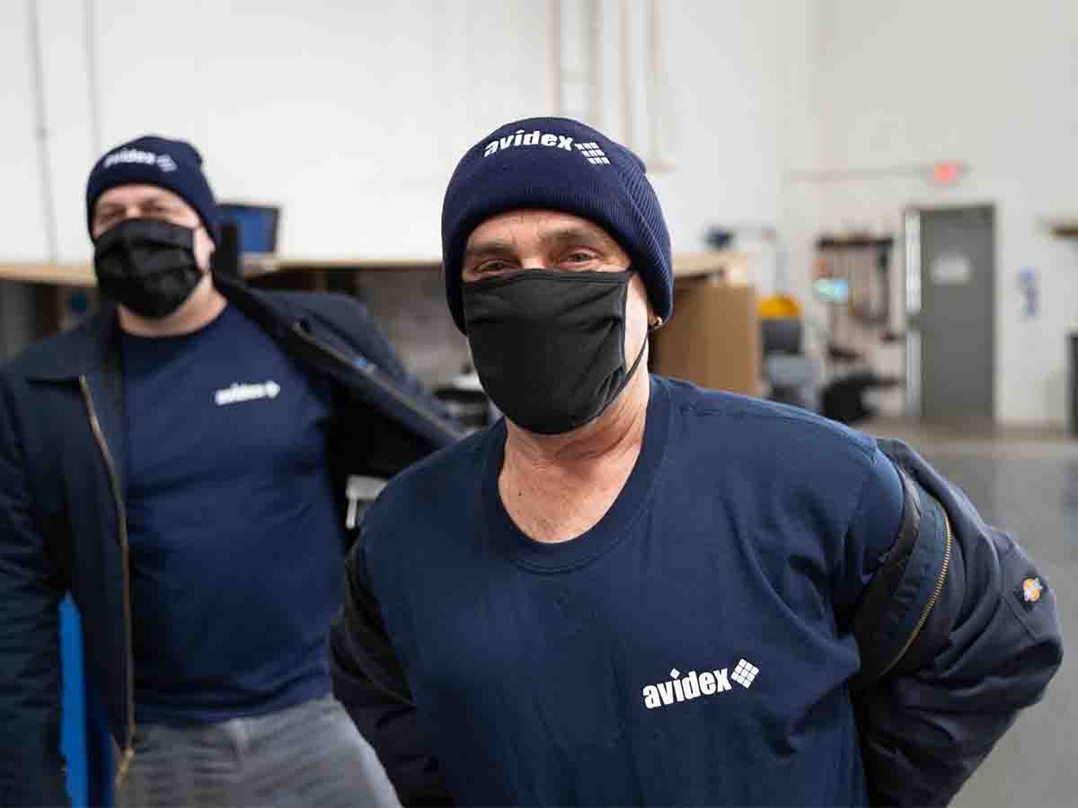 Two Avidex warehouse team members presenting new branded blue shirts