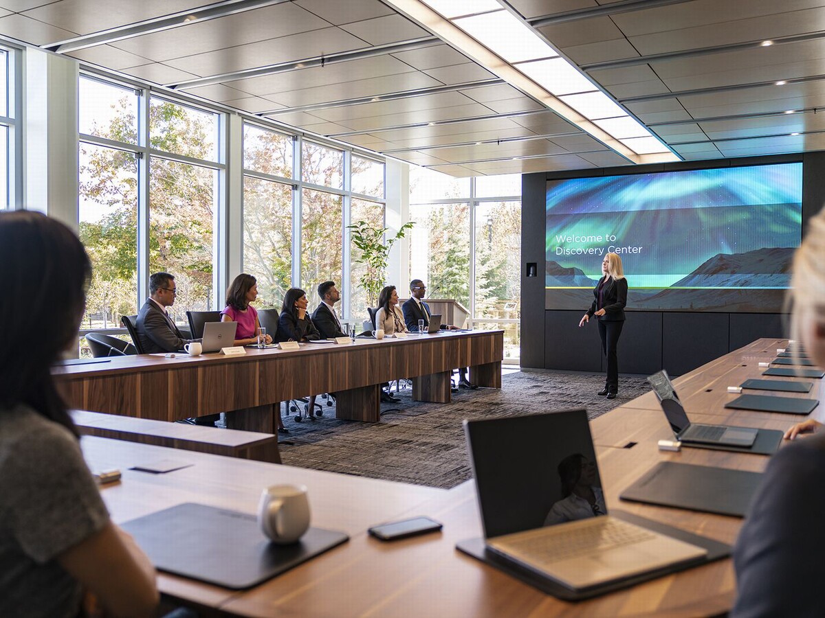 A woman giving a presentation in an executive boardroom using a large display and other AV solutions
