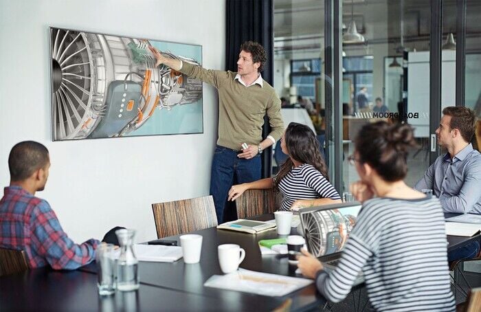 A group of colleagues collaborating in a room with a television